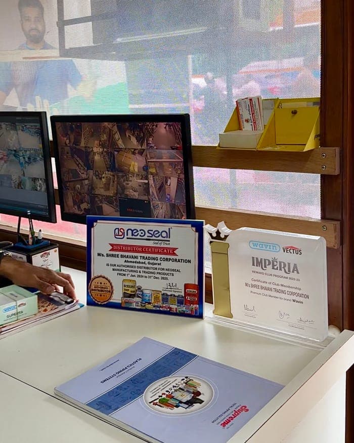 Framed dealer certificates on the counter: a NeoSeal distributor certificate and a Wavin Vectus Imperia membership, both naming Shree Bhavani Trading Corporation.